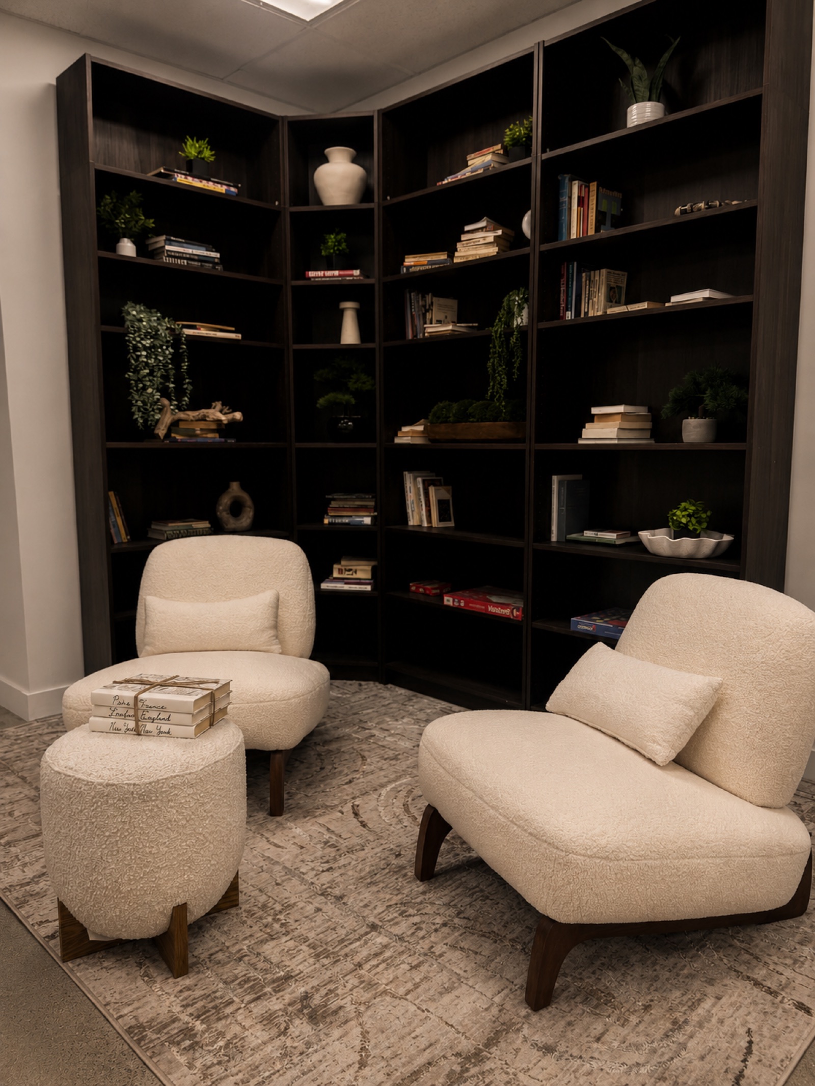 Quiet reading nook with bouclé chairs and floor-to-ceiling library shelves
